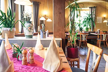 verschiedene Tische mit Abtrennung durch Blumen und Deko im hinteren Raum der Wallmüller Stuben