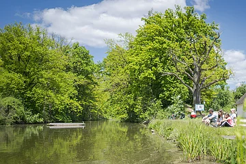 Familie sitzt mit Blick auf dem Karlsgraben. In der Mitte sieht man ein Kanu schwimmen.