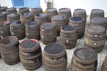 Ein Anzahl an Holzfässern steht auf gepflastertem Grund