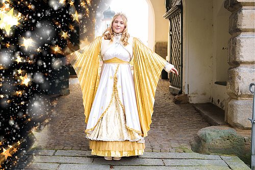 Das Christkind steht im Torbogen des Stadtschlosses und breitet seine Arme aus. So sieht man die Flügel des prächtigen goldenen Gewandes.