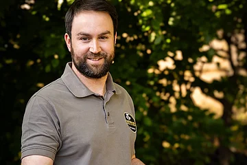 Der Metzger Walther Tim hält ein großes Holzbrett vor seinen Bauch. auf diesem Brett befinden sich seine selbstgemachten fränkische Wurstspezialitäten.